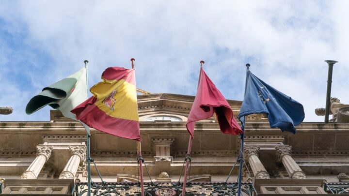 flags waving on old ornate city building on fine day